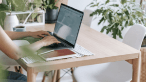 woman typing at computer desk near plants
